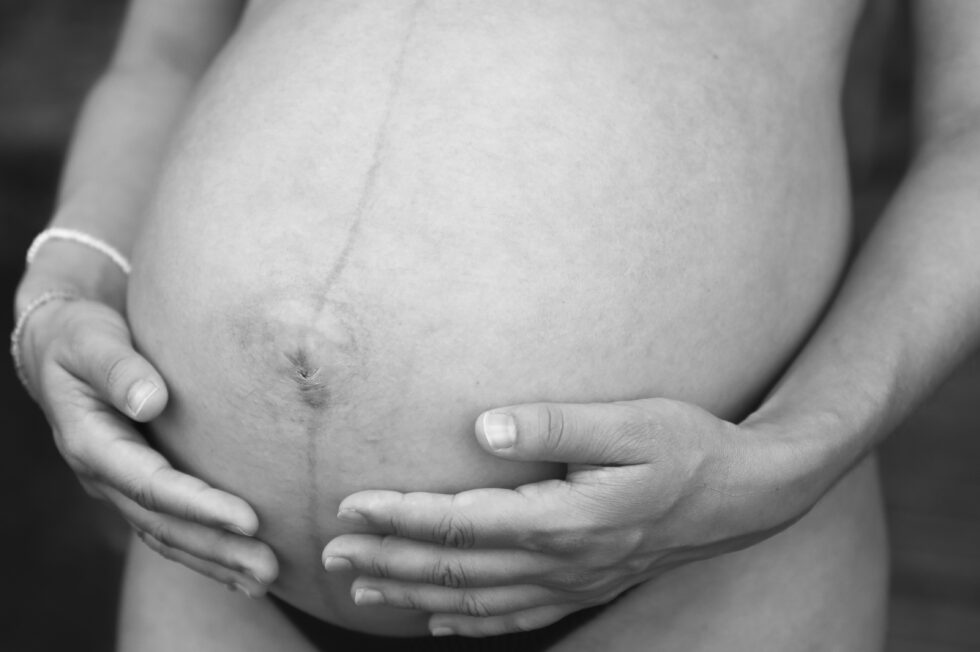 Nahaufnahme eines Babybauchs mit Hand einer Frau