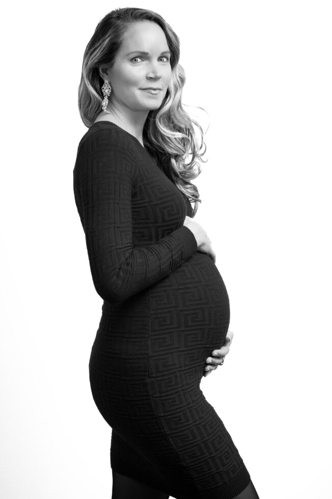 Schwangerschaftsportrait in seitlicher Pose, Frau trägt schwarzen Pullover