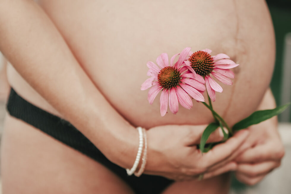 Nahaufnahme eines Babybauchs mit rosa Blume