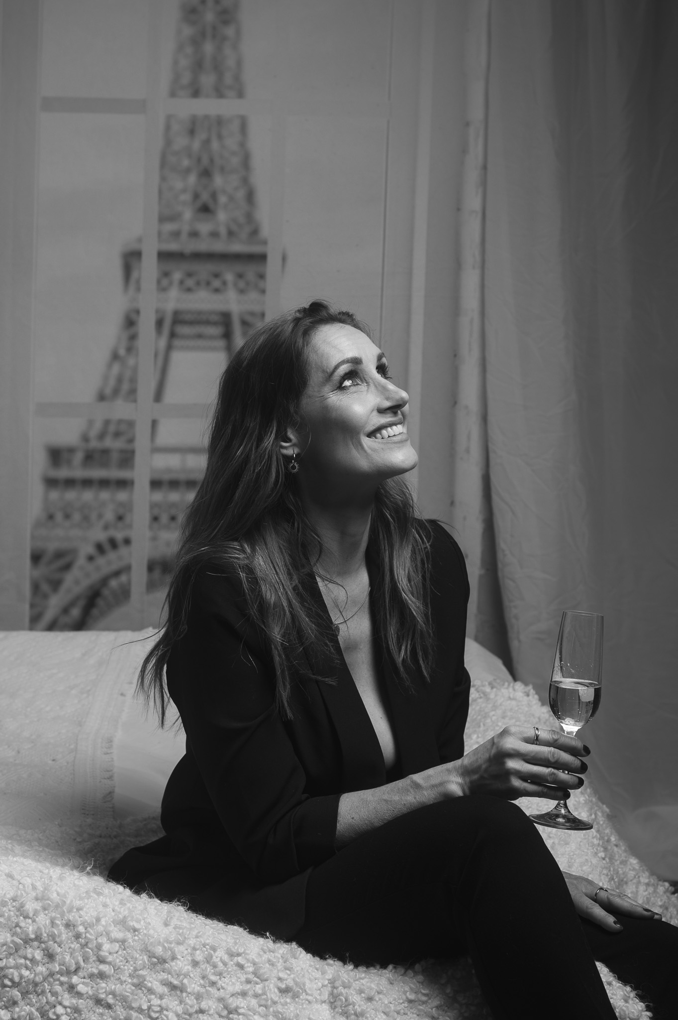 Eine Frau, lachend, mit ein Glas Champagne, Im Hintergrund den Eiffelturm.